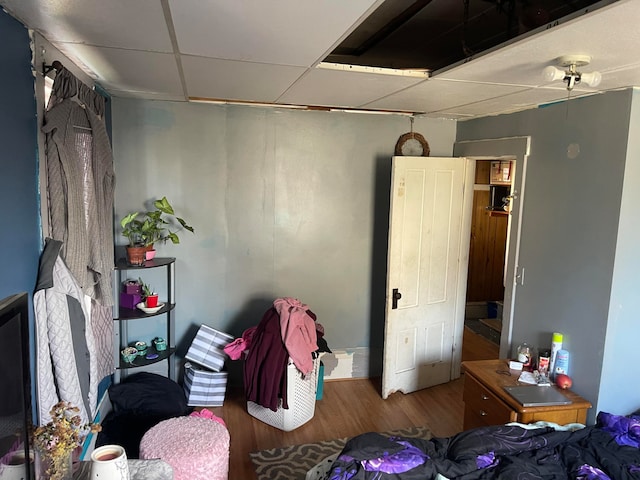 bedroom with a drop ceiling and wood-type flooring