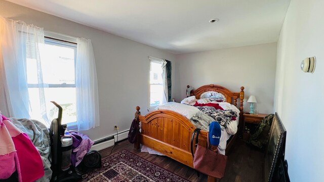 bedroom featuring baseboard heating, dark wood-type flooring, and multiple windows