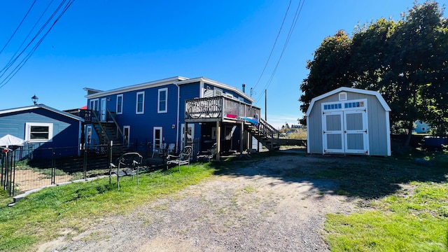 rear view of house with a deck and a storage unit