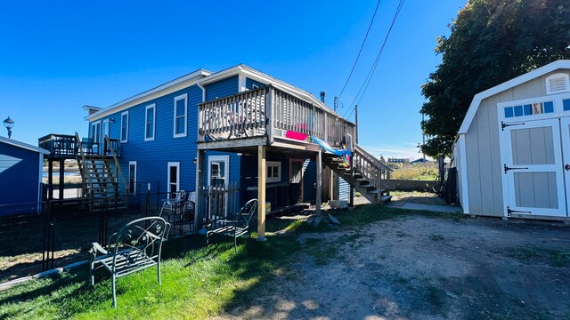 rear view of property with a storage unit and a deck