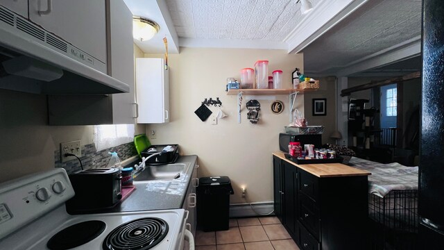 kitchen with white range, butcher block counters, sink, light tile patterned floors, and a baseboard radiator