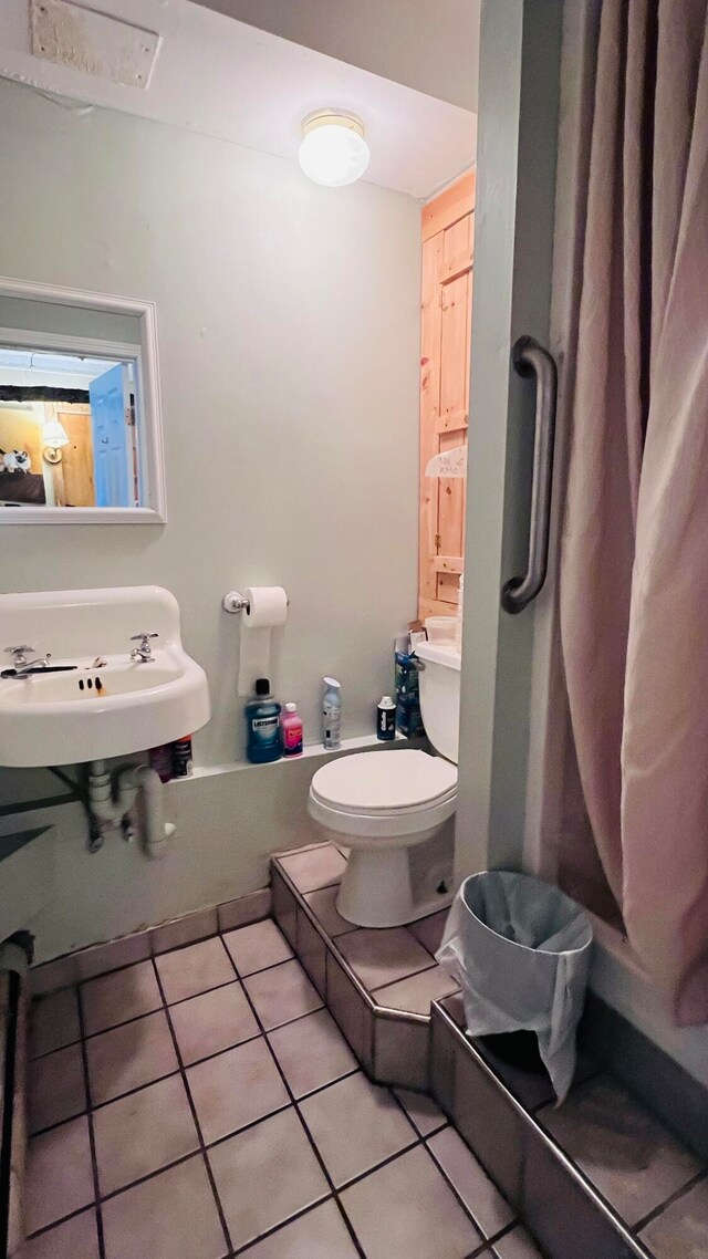 bathroom featuring toilet, sink, and tile patterned flooring