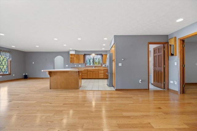 kitchen featuring light wood-type flooring, freestanding refrigerator, plenty of natural light, and light countertops