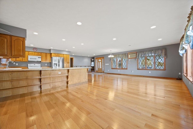 unfurnished living room with recessed lighting, baseboards, light wood-type flooring, and a sink