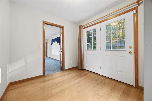 doorway to outside with baseboards and light wood finished floors