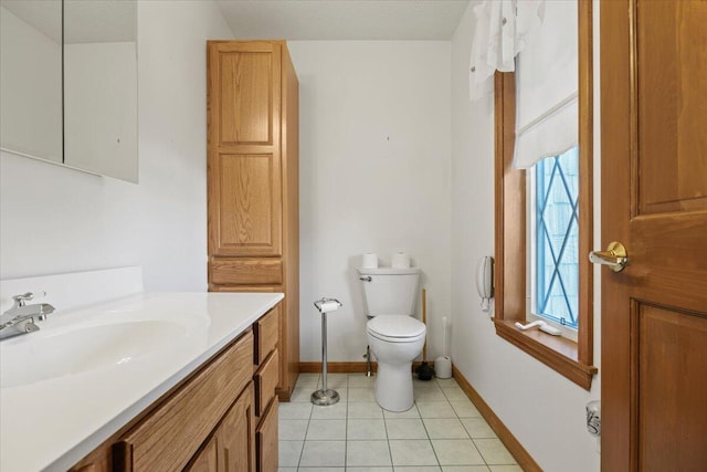 half bath with toilet, baseboards, tile patterned flooring, and vanity