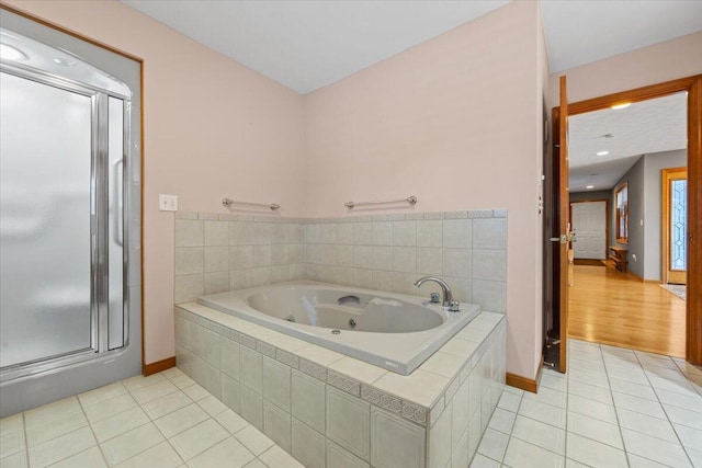 full bath with a tub with jets, baseboards, a shower stall, and tile patterned flooring