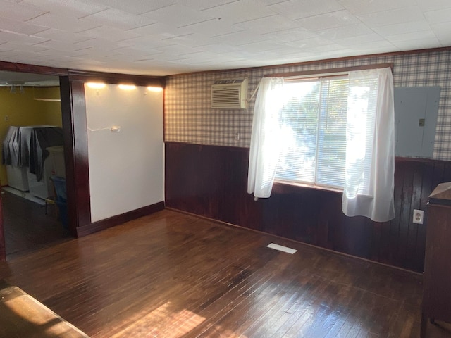 empty room with wood walls, a wall mounted AC, electric panel, and dark hardwood / wood-style floors