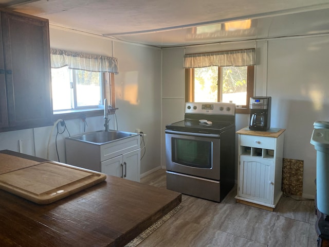 kitchen with white cabinets, a wealth of natural light, sink, and stainless steel electric range oven