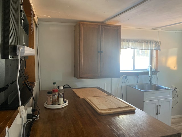 kitchen with ornamental molding, light hardwood / wood-style flooring, white cabinets, and sink