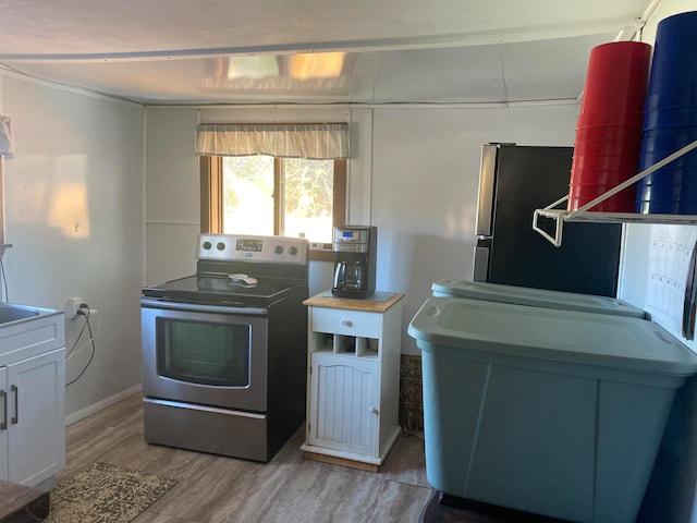 kitchen with appliances with stainless steel finishes, white cabinetry, and light hardwood / wood-style floors