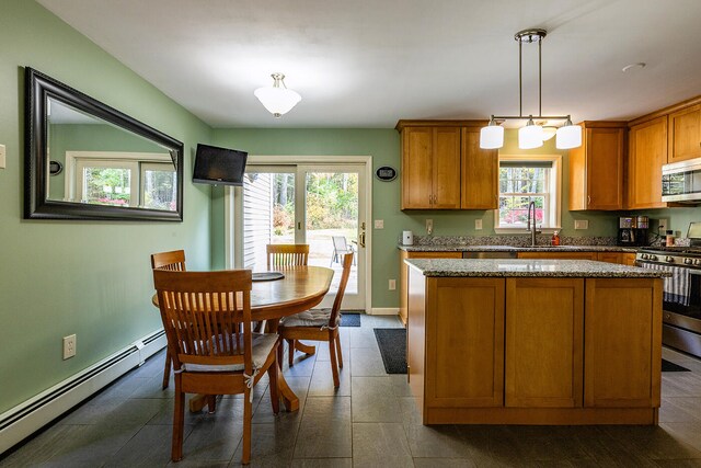 kitchen featuring a wealth of natural light, a baseboard radiator, appliances with stainless steel finishes, and hanging light fixtures