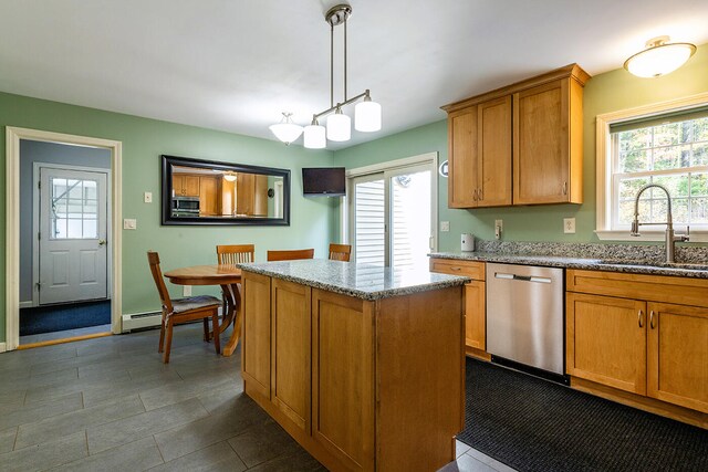 kitchen featuring hanging light fixtures, light stone countertops, stainless steel appliances, sink, and a center island