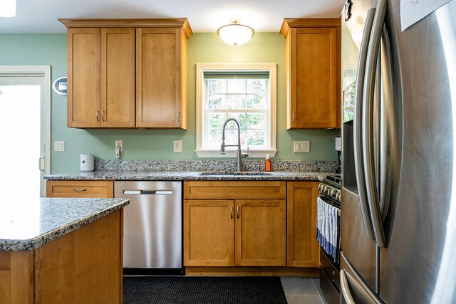 kitchen featuring dark tile patterned floors, stainless steel appliances, sink, and light stone counters