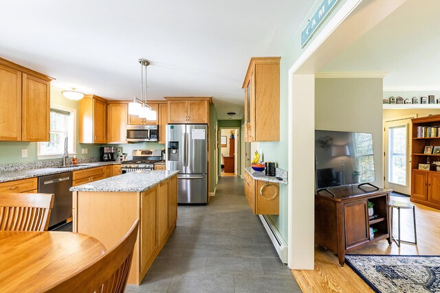 kitchen featuring a healthy amount of sunlight, appliances with stainless steel finishes, decorative light fixtures, and a kitchen island