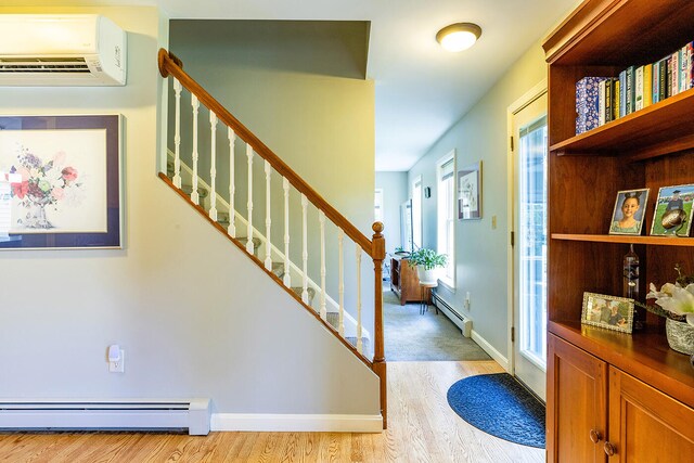 foyer entrance featuring a wall mounted AC, a baseboard radiator, and light wood-type flooring