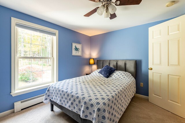 carpeted bedroom featuring multiple windows, a baseboard radiator, and ceiling fan