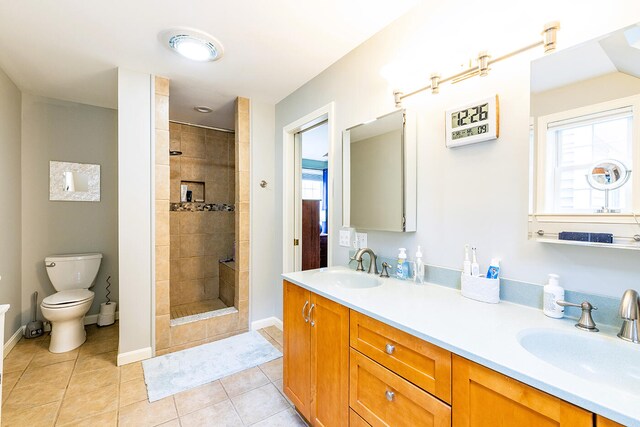 bathroom featuring a tile shower, toilet, tile patterned flooring, and vanity