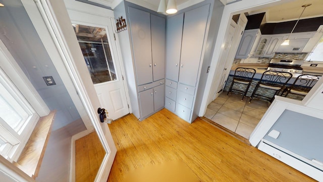 kitchen with hanging light fixtures, backsplash, gray cabinets, a baseboard radiator, and light hardwood / wood-style floors