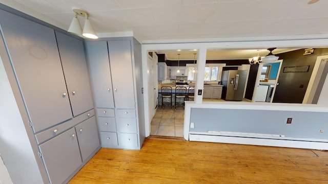 kitchen featuring a baseboard heating unit, an inviting chandelier, light hardwood / wood-style flooring, gray cabinetry, and stainless steel refrigerator with ice dispenser