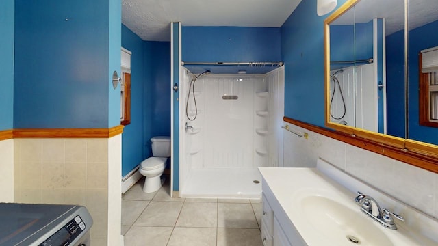 bathroom with washer / clothes dryer, toilet, tile walls, a shower, and tile patterned flooring