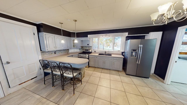 kitchen with kitchen peninsula, sink, an inviting chandelier, light tile patterned floors, and appliances with stainless steel finishes