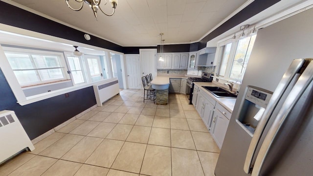 kitchen with appliances with stainless steel finishes, radiator, ceiling fan with notable chandelier, crown molding, and sink