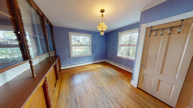 unfurnished dining area with a baseboard radiator, light hardwood / wood-style flooring, and a textured ceiling