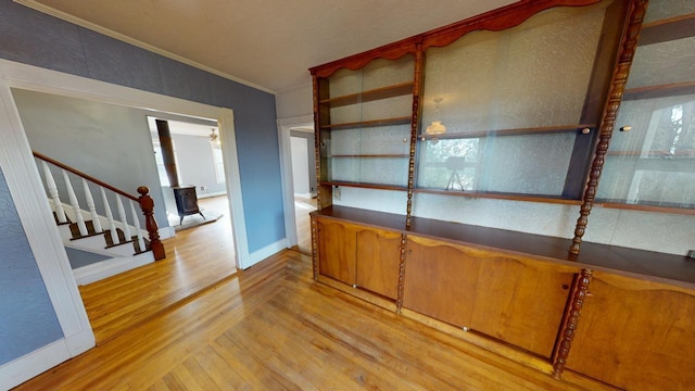 interior space featuring ornamental molding, light wood-type flooring, and a wood stove