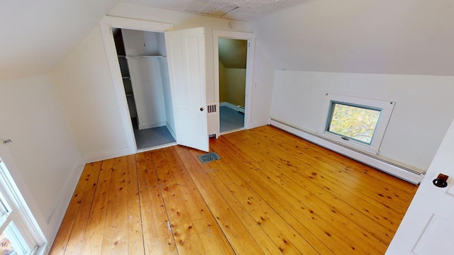 bonus room with a baseboard radiator, hardwood / wood-style flooring, and lofted ceiling