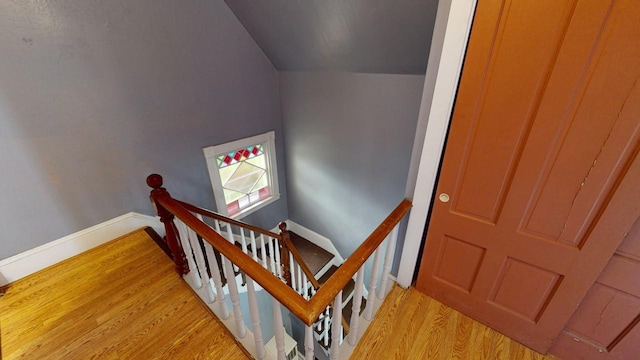 stairs featuring hardwood / wood-style floors and vaulted ceiling