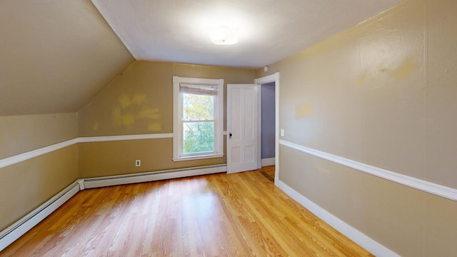 additional living space with baseboard heating, vaulted ceiling, and light hardwood / wood-style floors