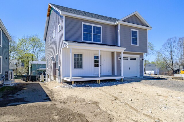 view of front of property with a garage, dirt driveway, a porch, and central air condition unit