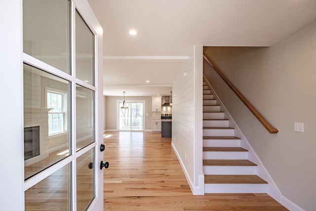 stairway with baseboards, a notable chandelier, a large fireplace, and wood finished floors