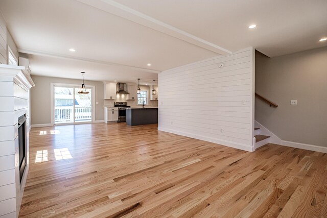 unfurnished living room with recessed lighting, baseboards, light wood-style flooring, and a fireplace