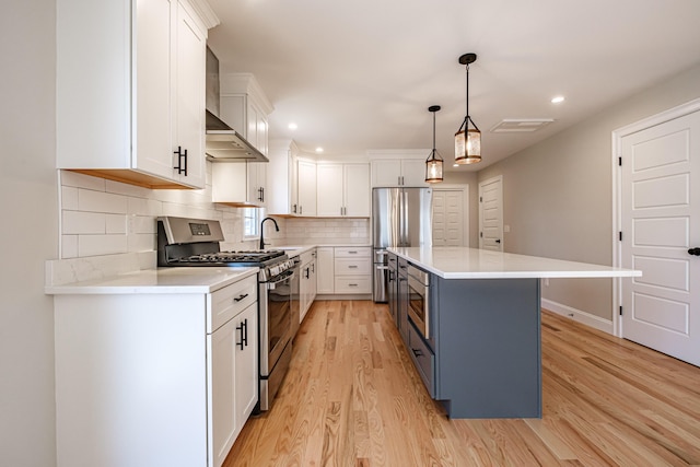 kitchen with a kitchen island, light wood-style floors, light countertops, white cabinets, and appliances with stainless steel finishes