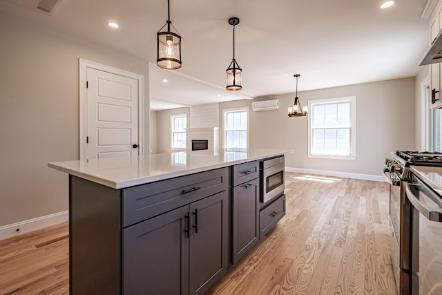 kitchen featuring baseboards, appliances with stainless steel finishes, gray cabinets, and a wall mounted air conditioner