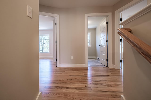corridor with light wood-type flooring and baseboards