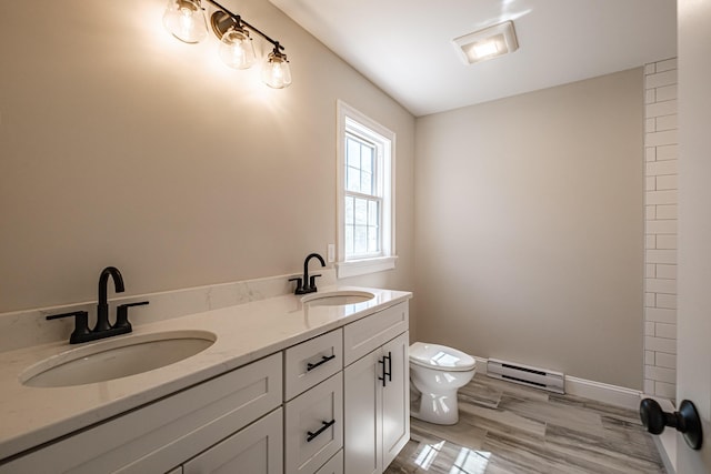 bathroom with double vanity, a sink, a baseboard radiator, and toilet