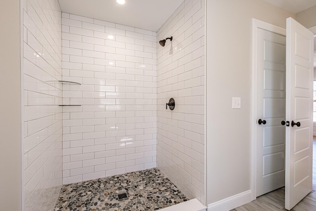 bathroom with recessed lighting, baseboards, and a tile shower
