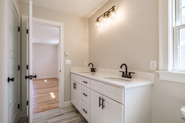 full bathroom with double vanity, a sink, baseboards, and toilet