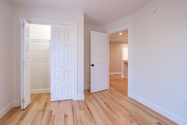 unfurnished bedroom with a closet, light wood finished floors, and baseboards