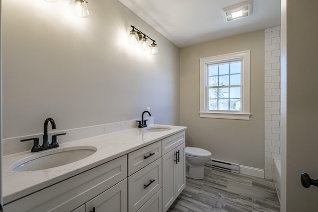 full bathroom featuring a shower, a sink, a baseboard heating unit, and toilet