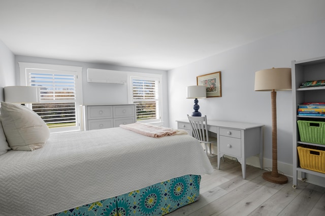 bedroom featuring a wall mounted AC, multiple windows, and light wood-type flooring