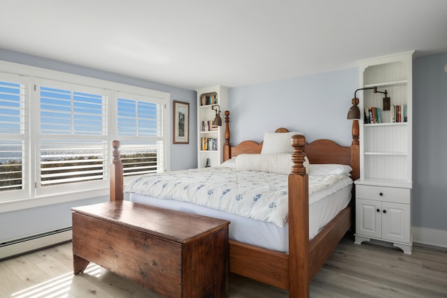 bedroom with wood-type flooring and a baseboard heating unit