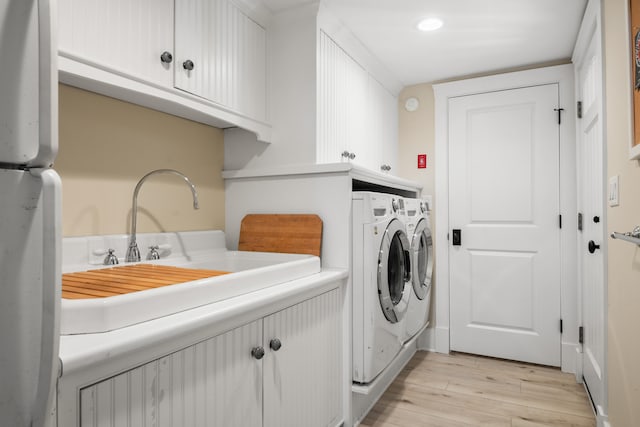 laundry area with cabinets, sink, light wood-type flooring, and washing machine and clothes dryer