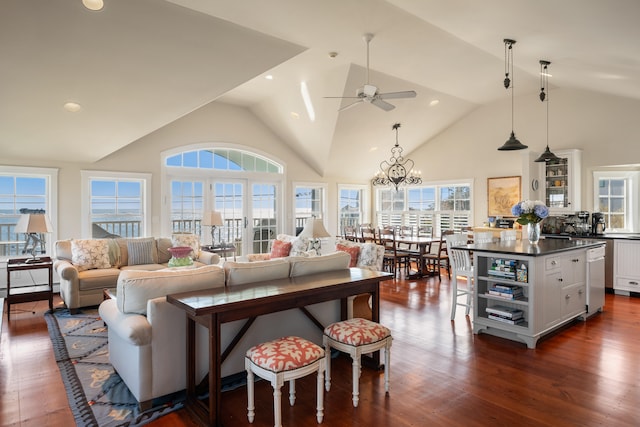 living room with ceiling fan with notable chandelier, high vaulted ceiling, and dark hardwood / wood-style floors