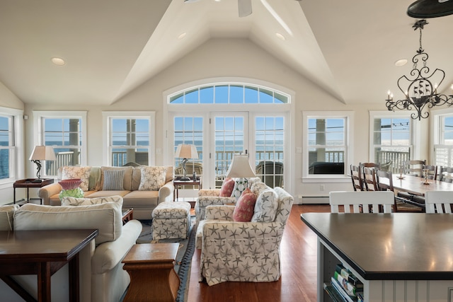 living room with vaulted ceiling, dark hardwood / wood-style floors, a healthy amount of sunlight, and ceiling fan with notable chandelier