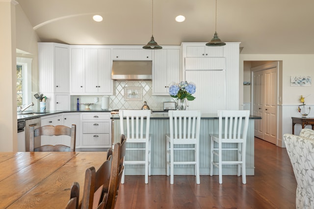 kitchen featuring wall chimney exhaust hood, sink, pendant lighting, white cabinetry, and dark hardwood / wood-style flooring