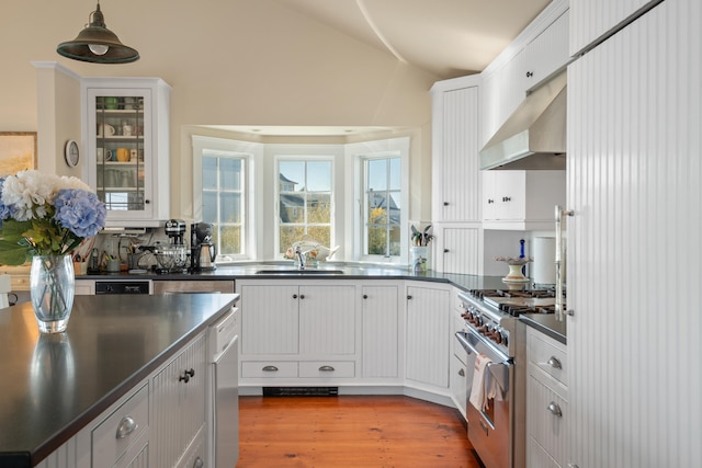 kitchen with white cabinets, wall chimney range hood, hardwood / wood-style floors, and high end range